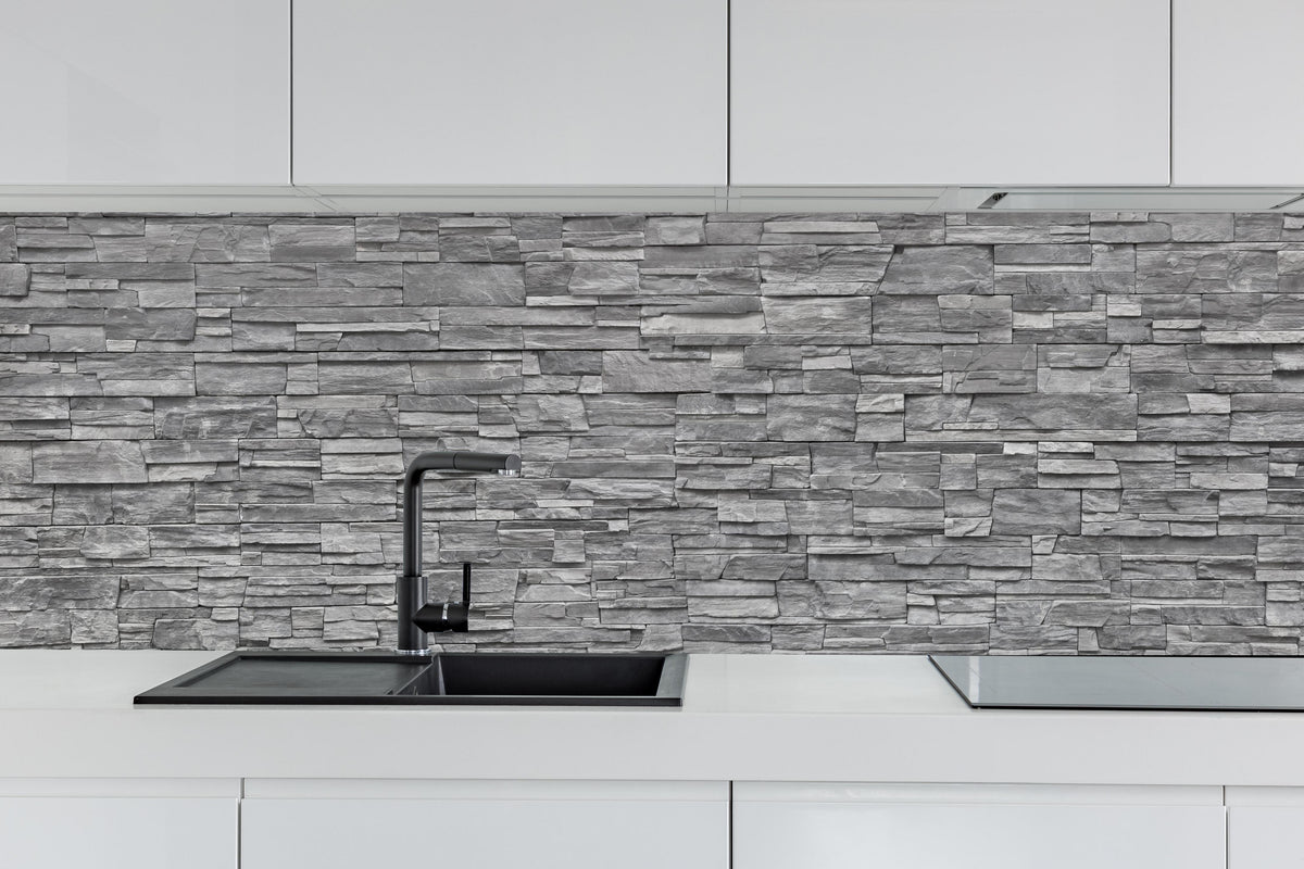 Küche - Graue Steinwand hinter weißen Hochglanz-Küchenregalen und schwarzem Wasserhahn