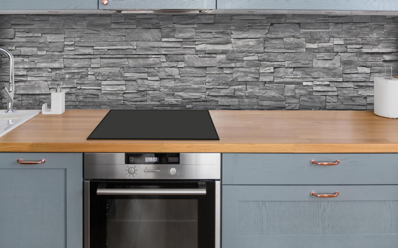 Küche - Graue Steinwand über polierter Holzarbeitsplatte mit Cerankochfeld