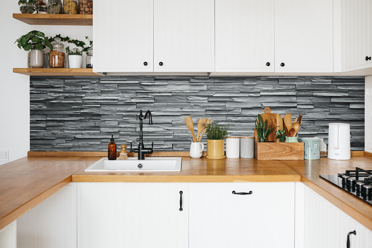 Küche - Graue Steinziegel in weißer Küche hinter Gewürzen und Kochlöffeln aus Holz