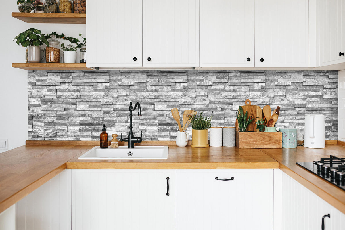 Küche - Graue moderne Ziegelwand in weißer Küche hinter Gewürzen und Kochlöffeln aus Holz