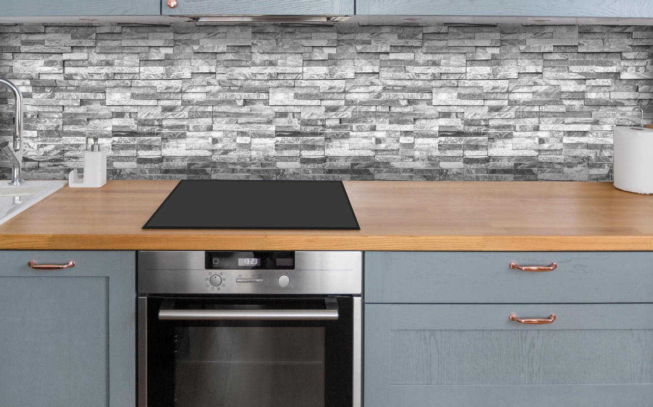 Küche - Graue moderne Ziegelwand über polierter Holzarbeitsplatte mit Cerankochfeld