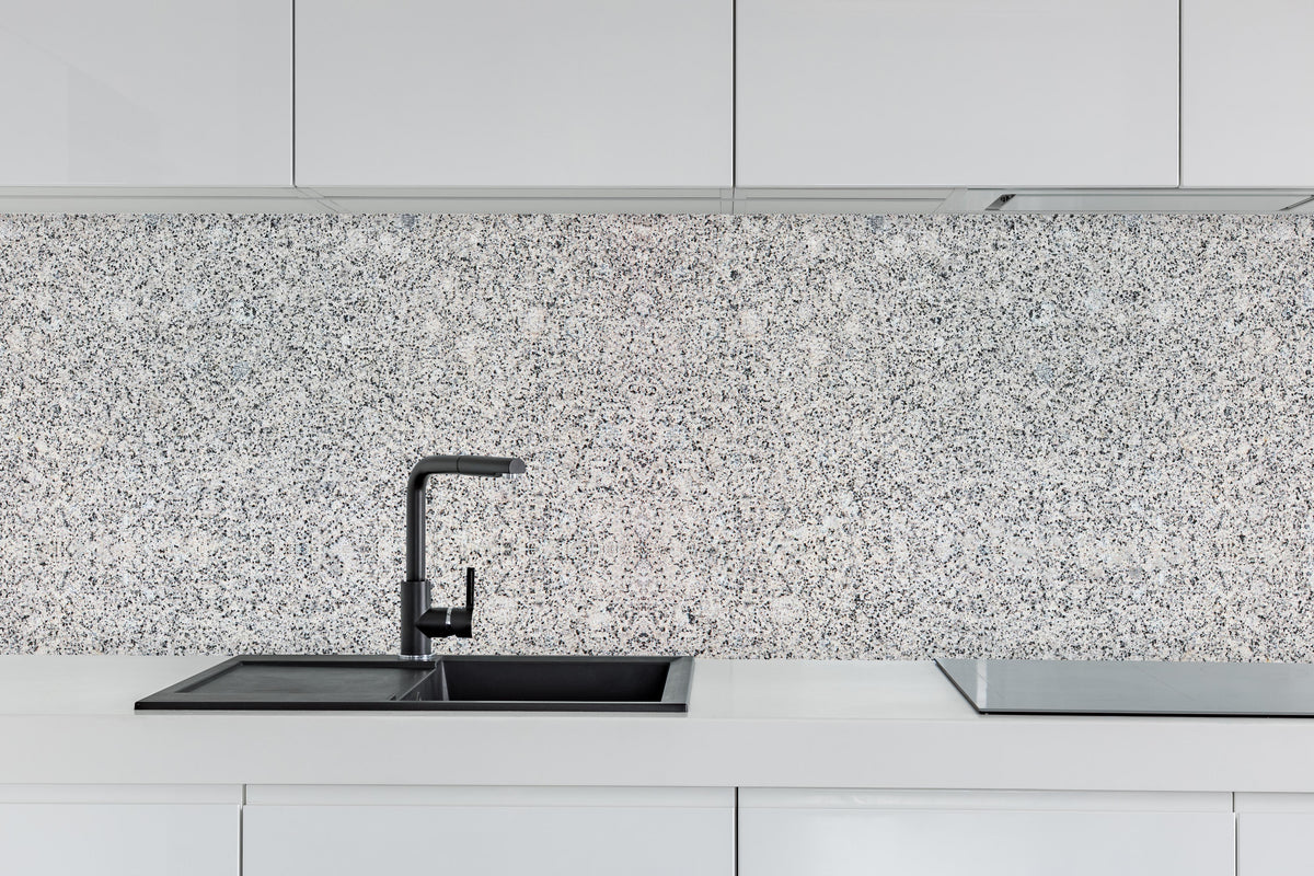 Küche - Grauer Granit hinter weißen Hochglanz-Küchenregalen und schwarzem Wasserhahn
