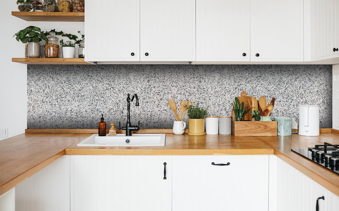 Küche - Grauer Granit in weißer Küche hinter Gewürzen und Kochlöffeln aus Holz