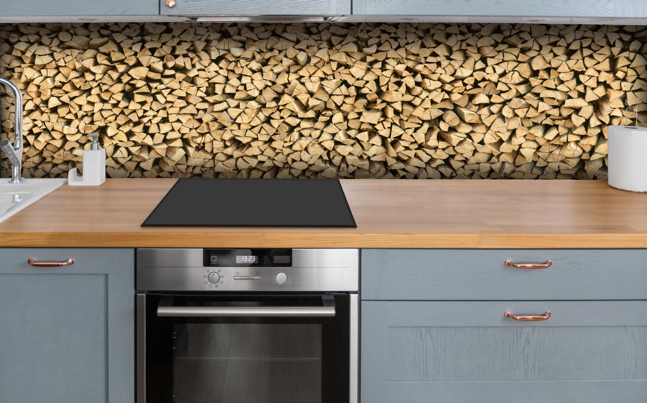 Küche - Großer Haufen Holzscheite über polierter Holzarbeitsplatte mit Cerankochfeld