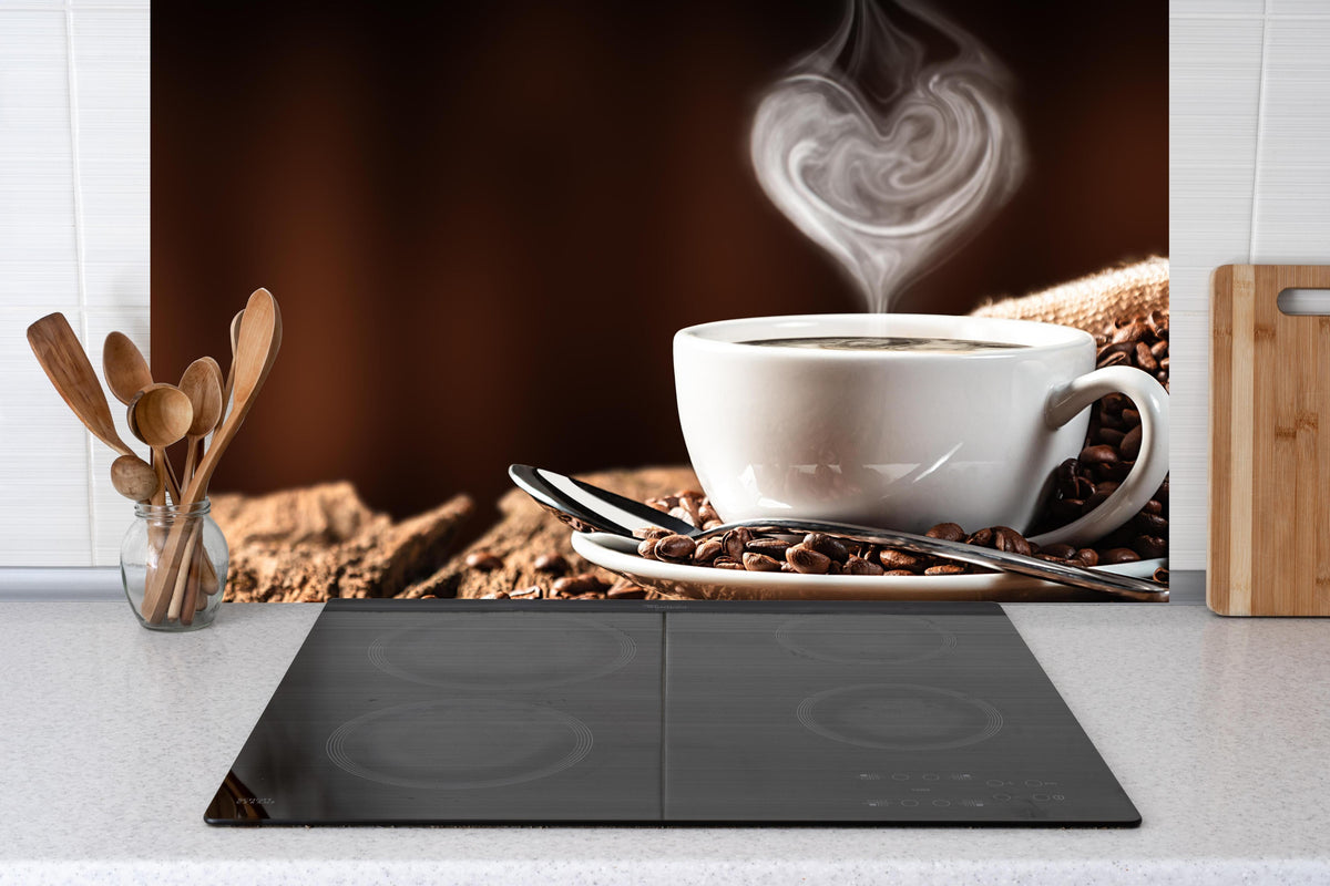 Küche - Kaffeetasse mit herzförmigem Dampf hinter Cerankochfeld und Holz-Kochutensilien
