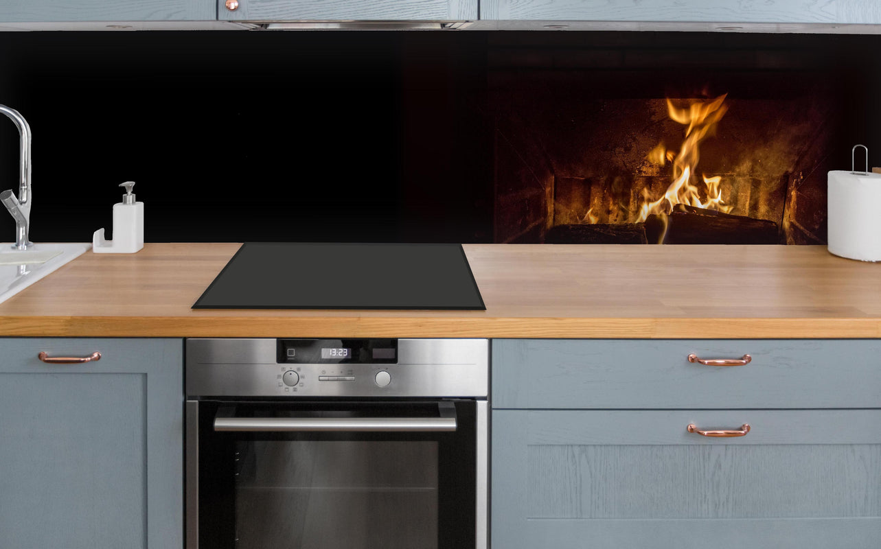 Küche - Kaminfeuer vor Holztisch über polierter Holzarbeitsplatte mit Cerankochfeld