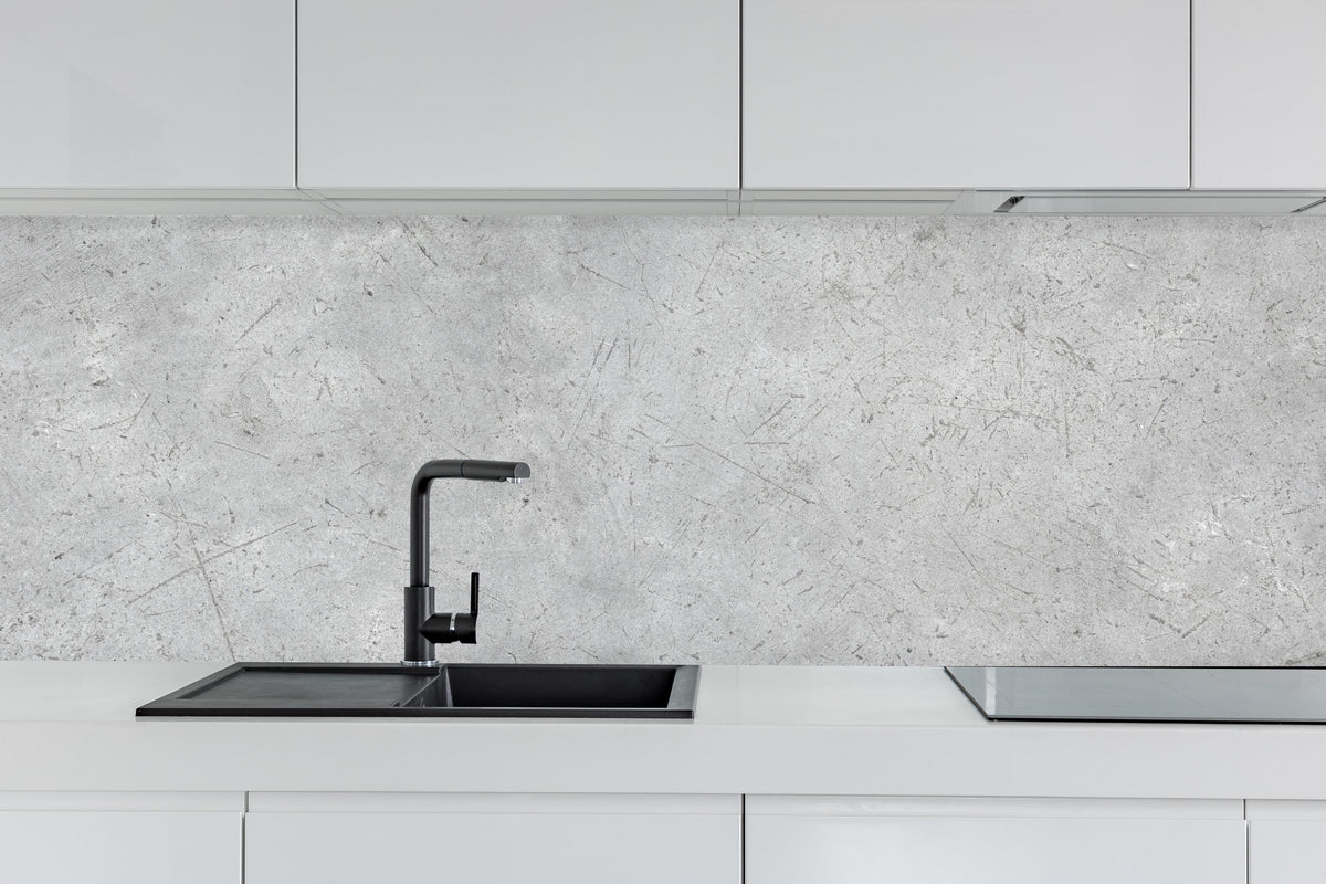 Küche - Kratzige graue Betonwand hinter weißen Hochglanz-Küchenregalen und schwarzem Wasserhahn
