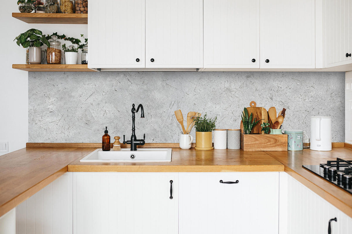 Küche - Kratzige graue Betonwand in weißer Küche hinter Gewürzen und Kochlöffeln aus Holz