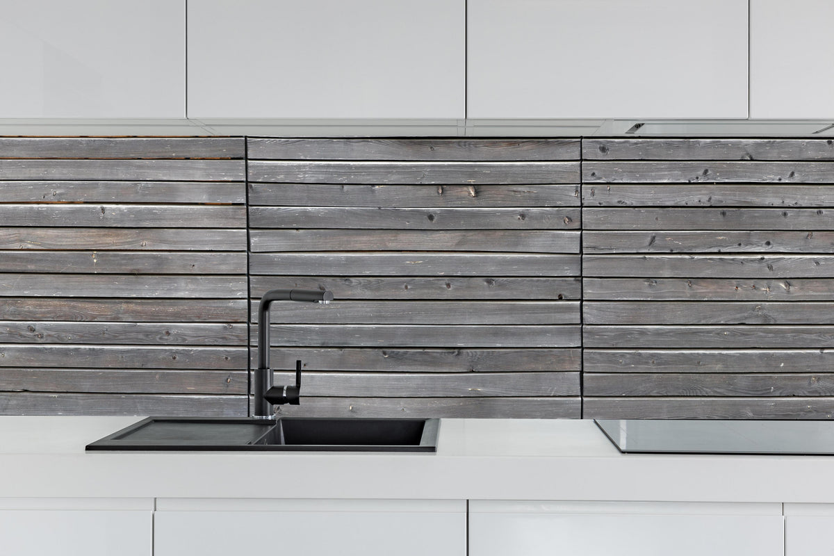 Küche - Langer grauer Holzzaun hinter weißen Hochglanz-Küchenregalen und schwarzem Wasserhahn