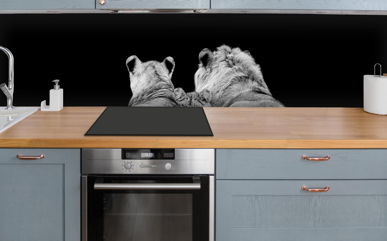 Küche - Löwenfamilie liegend mit schwarzem Hintergrund über polierter Holzarbeitsplatte mit Cerankochfeld