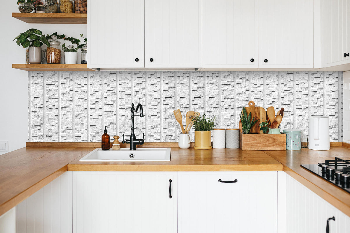 Küche - Modern weiße Steinwand mit Muster in weißer Küche hinter Gewürzen und Kochlöffeln aus Holz