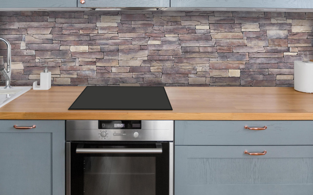 Küche - Natursteinmauer aus Sandstein über polierter Holzarbeitsplatte mit Cerankochfeld