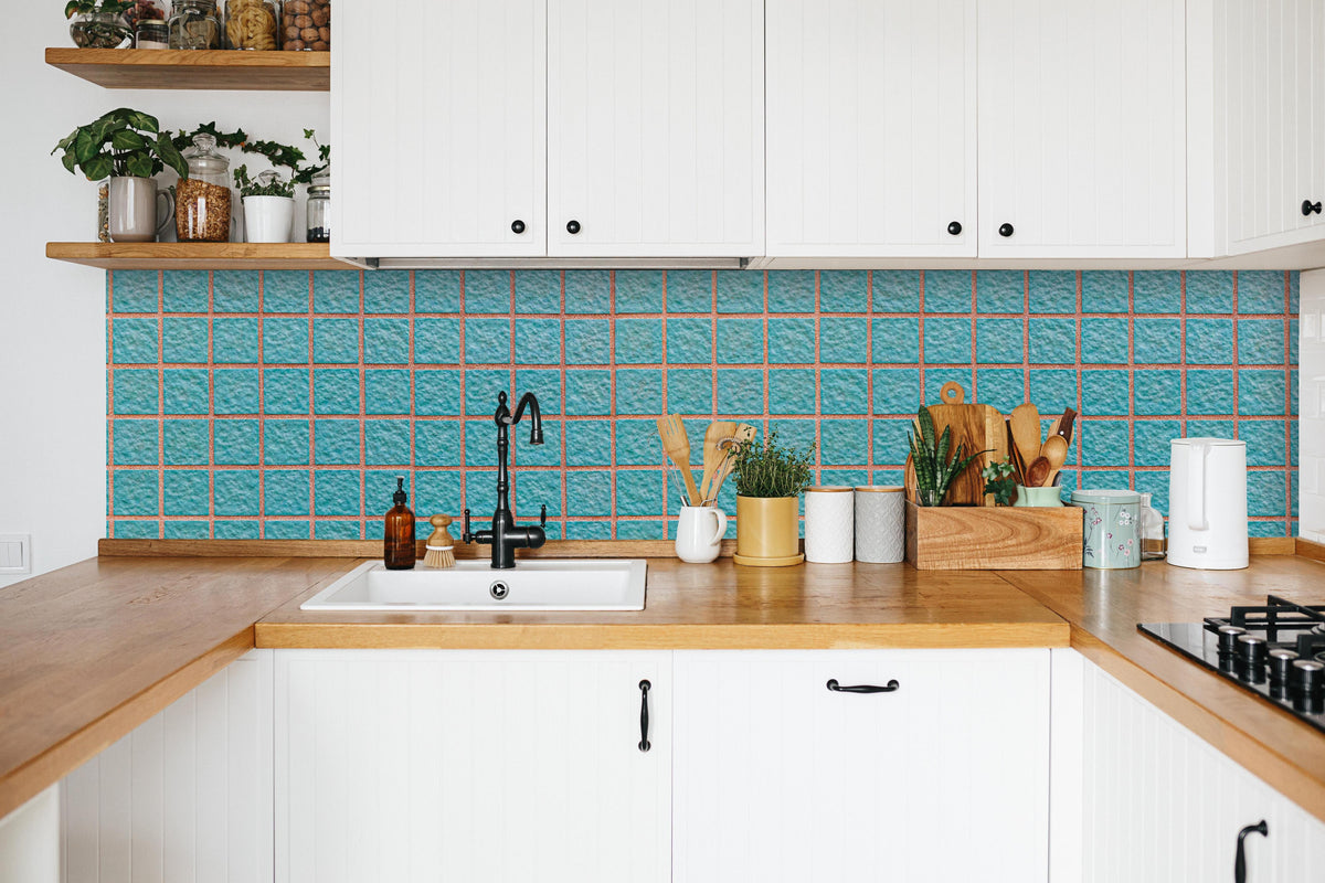 Küche - Panorama der hellblauen Steinblockwand in weißer Küche hinter Gewürzen und Kochlöffeln aus Holz