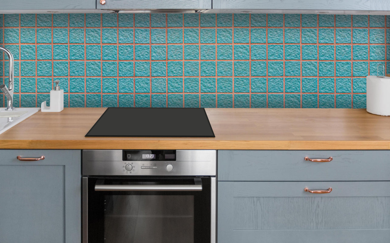Küche - Panorama der hellblauen Steinblockwand über polierter Holzarbeitsplatte mit Cerankochfeld