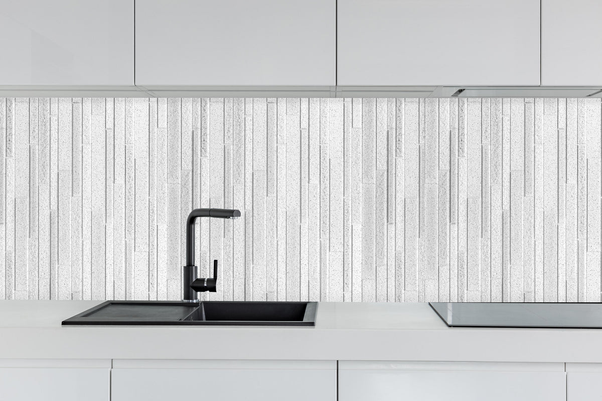 Küche - Panorama der weißen Granitblockwand hinter weißen Hochglanz-Küchenregalen und schwarzem Wasserhahn