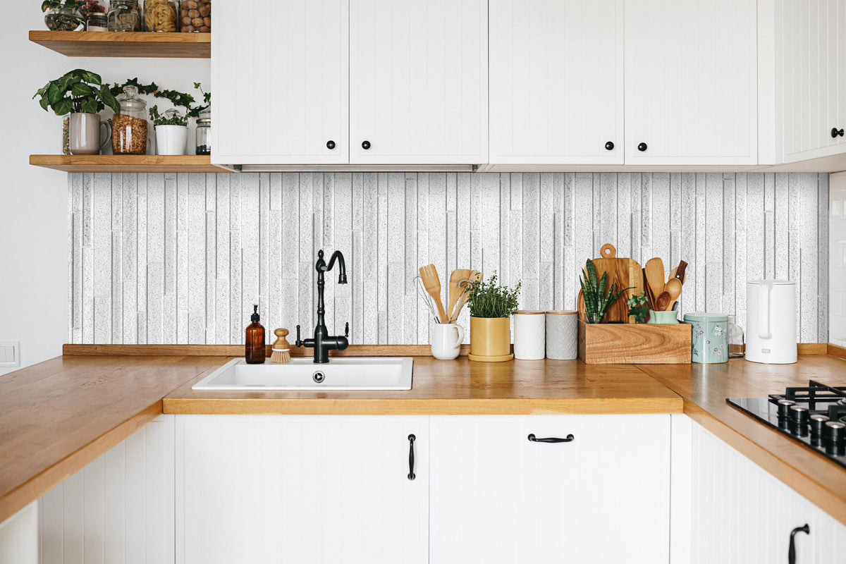 Küche - Panorama der weißen Granitblockwand in weißer Küche hinter Gewürzen und Kochlöffeln aus Holz