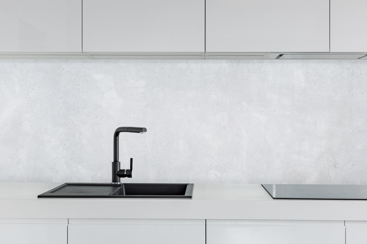 Küche - Panorama einer glatten grauen Betonwand hinter weißen Hochglanz-Küchenregalen und schwarzem Wasserhahn