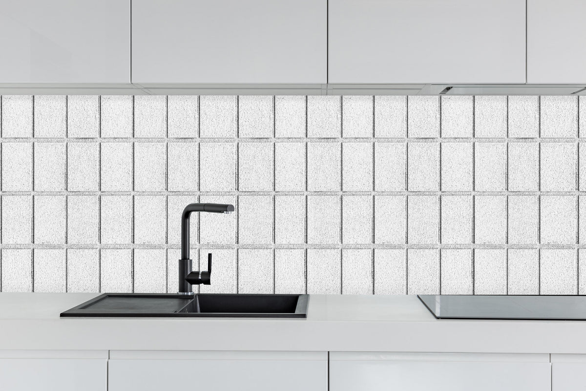 Küche - Panorama von weißem Betonblock Wand hinter weißen Hochglanz-Küchenregalen und schwarzem Wasserhahn