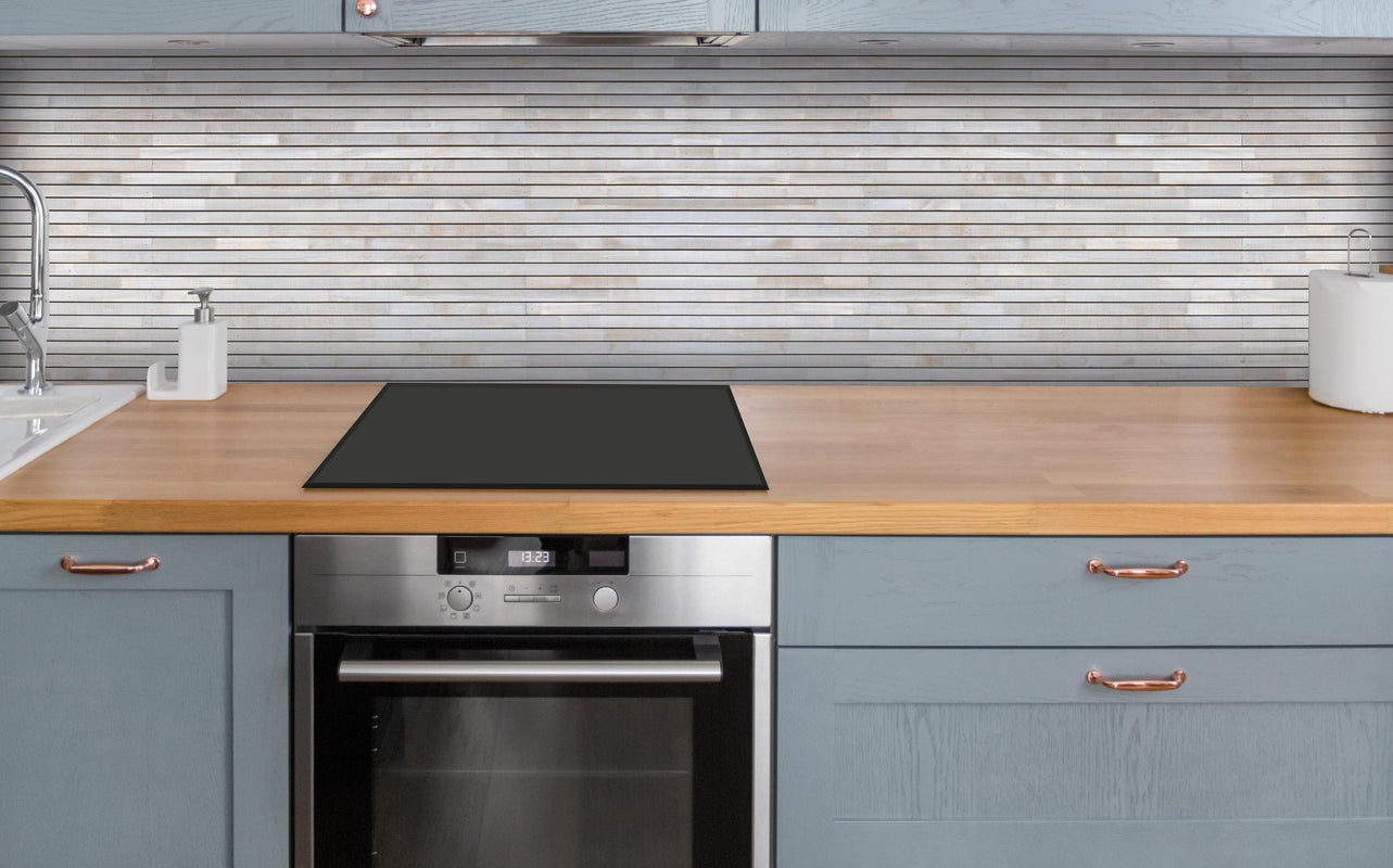 Küche - Pastellfarbige Holzfassade über polierter Holzarbeitsplatte mit Cerankochfeld