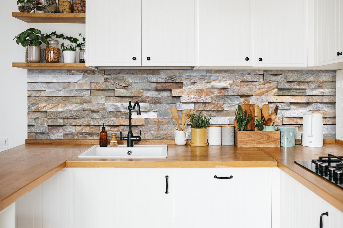Küche - Pastellfarbige Steinmauer in weißer Küche hinter Gewürzen und Kochlöffeln aus Holz