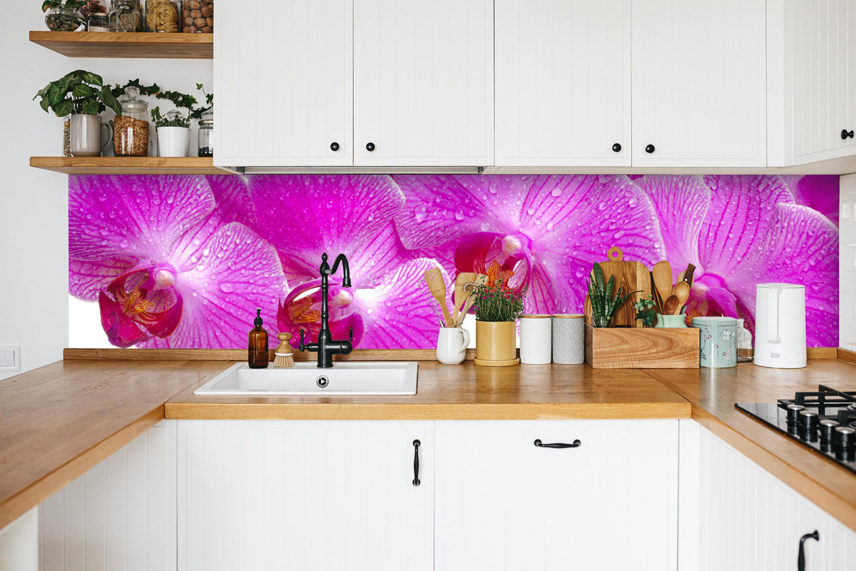 Küche - Pinke Orchideen in weißer Küche hinter Gewürzen und Kochlöffeln aus Holz