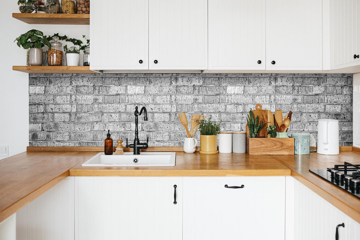 Küche - Raues hellgraues Mauerwerk in weißer Küche hinter Gewürzen und Kochlöffeln aus Holz