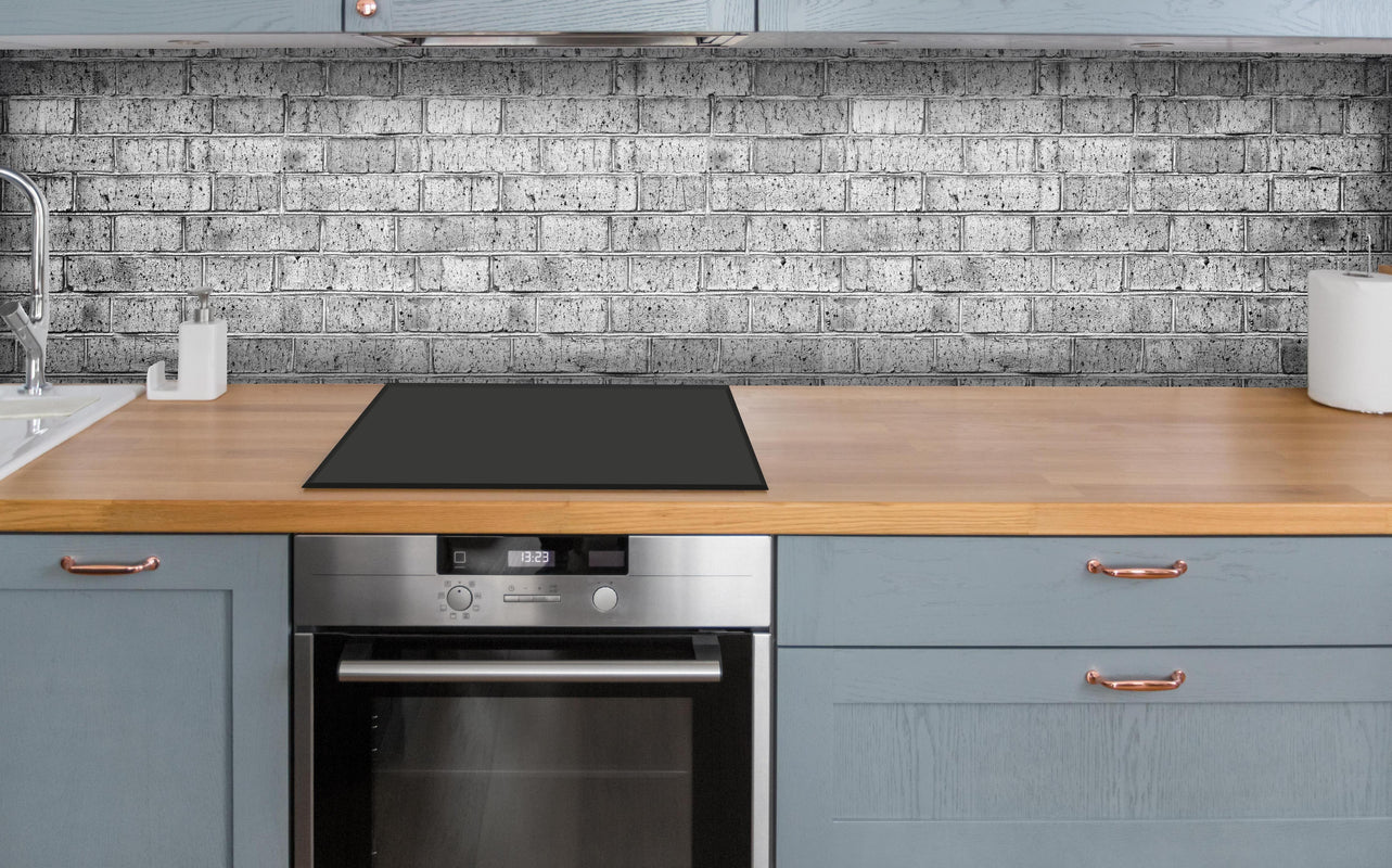 Küche - Raues hellgraues Mauerwerk über polierter Holzarbeitsplatte mit Cerankochfeld