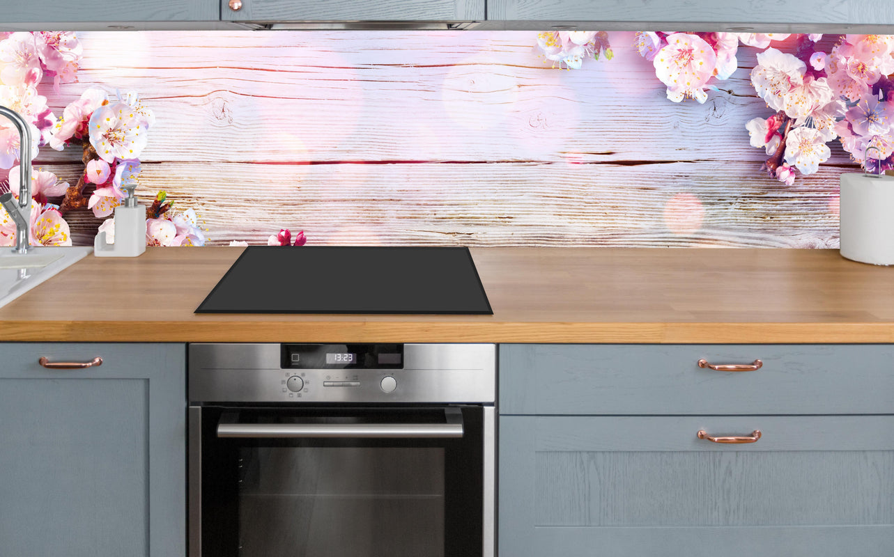 Küche - Rosa Blüten auf Holzplatte über polierter Holzarbeitsplatte mit Cerankochfeld