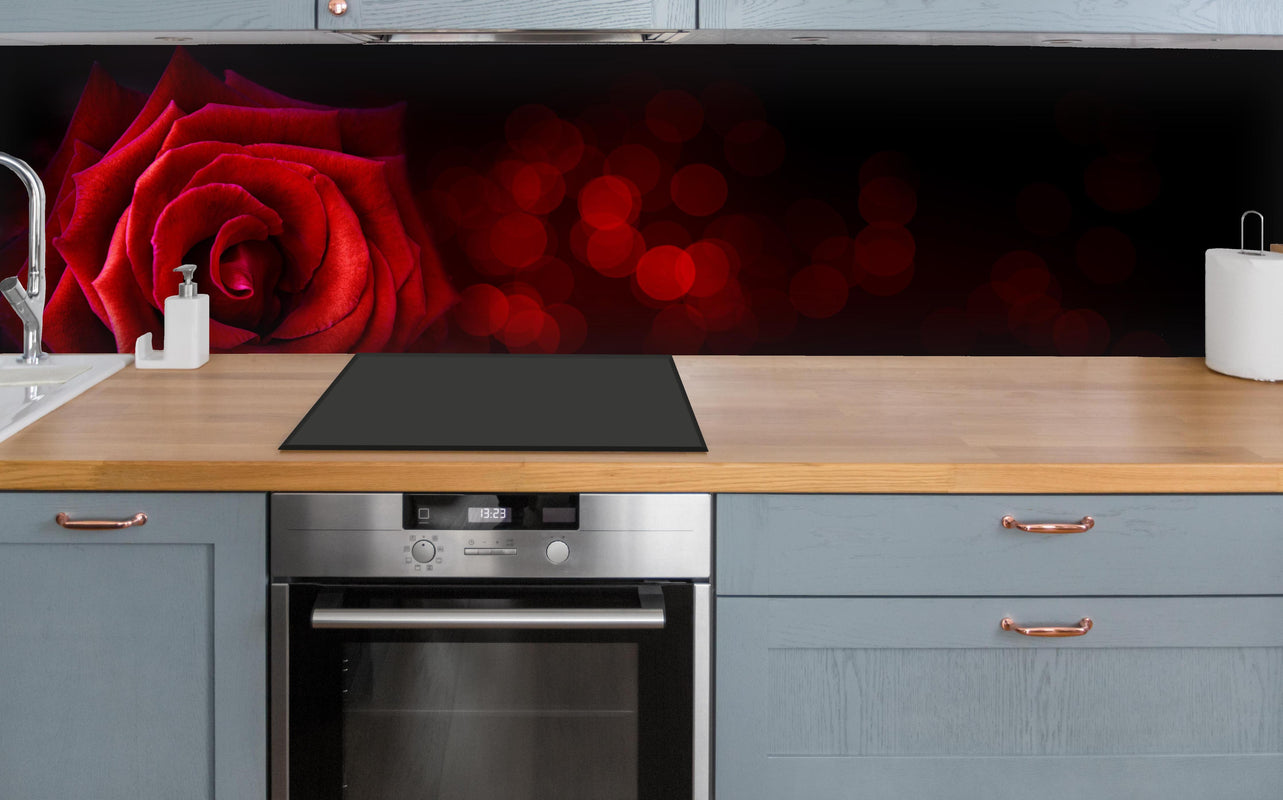 Küche - Rote Rose auf schwarzem Hintergrund über polierter Holzarbeitsplatte mit Cerankochfeld