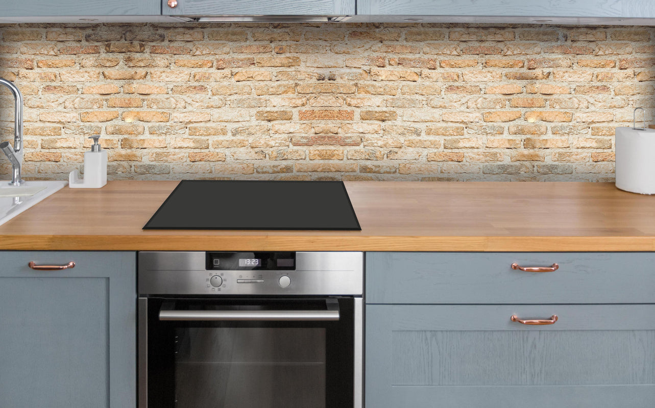 Küche - Rustikale Backsteinmauer über polierter Holzarbeitsplatte mit Cerankochfeld
