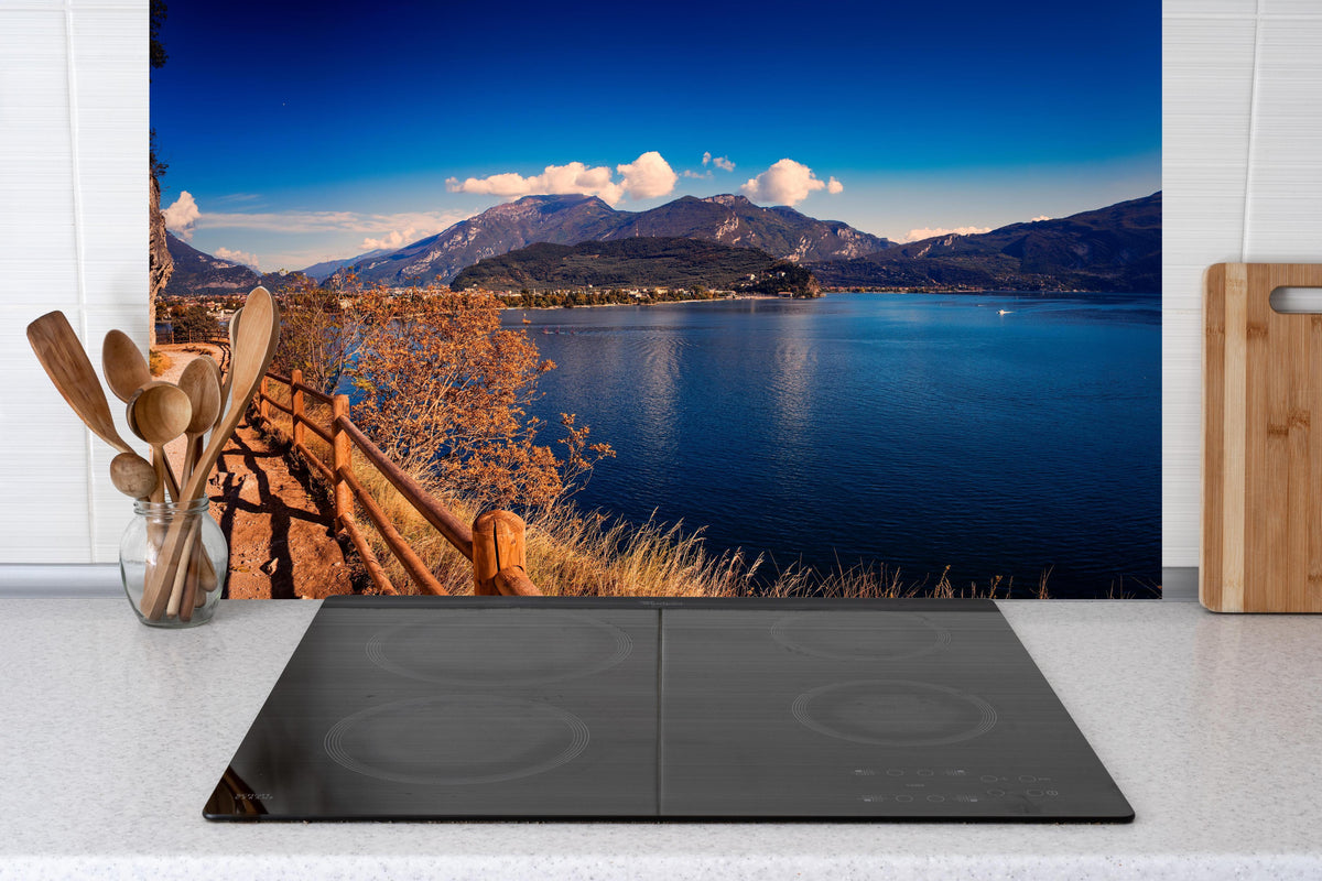 Küche - Schöne Landschaft mit Blick auf den Gardasee hinter Cerankochfeld und Holz-Kochutensilien