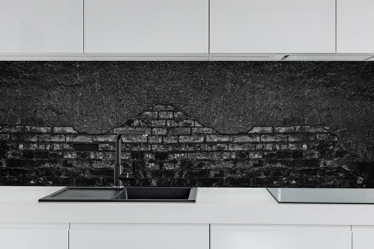 Küche - Schwarz gebrannte Ziegelwand mit abgefallenem Putz hinter weißen Hochglanz-Küchenregalen und schwarzem Wasserhahn
