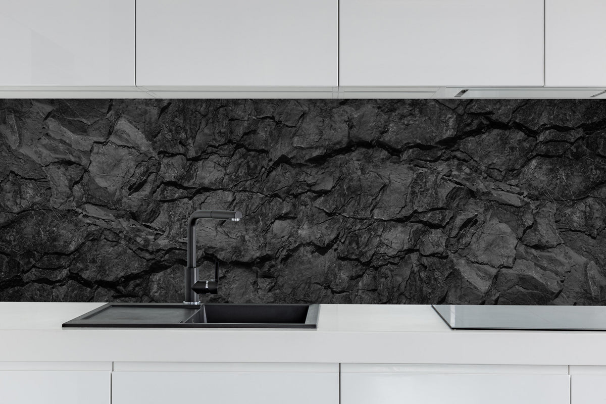 Küche - Schwarze Gesteinstextur mit Rissen hinter weißen Hochglanz-Küchenregalen und schwarzem Wasserhahn