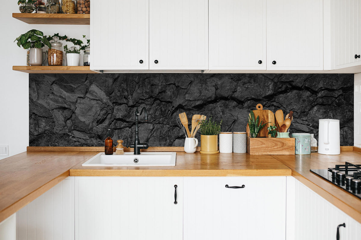 Küche - Schwarze Gesteinstextur mit Rissen in weißer Küche hinter Gewürzen und Kochlöffeln aus Holz