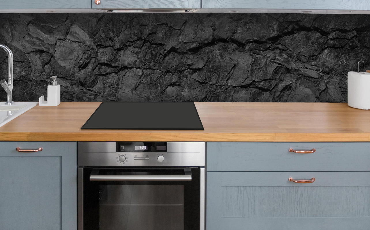 Küche - Schwarze Gesteinstextur mit Rissen über polierter Holzarbeitsplatte mit Cerankochfeld
