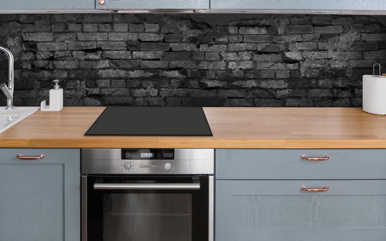 Küche - Schwarze alte Backsteinmauer über polierter Holzarbeitsplatte mit Cerankochfeld