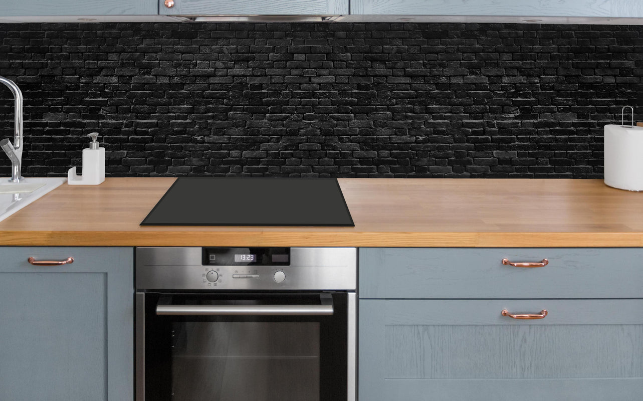 Küche - Schwarze raue Ziegelwand über polierter Holzarbeitsplatte mit Cerankochfeld