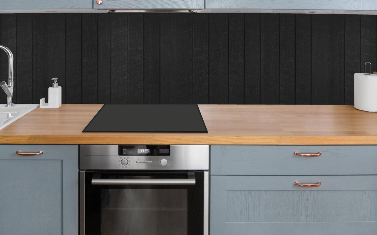 Küche - Schwarzer Holzzaun mit vertikalen Holzbrättern über polierter Holzarbeitsplatte mit Cerankochfeld