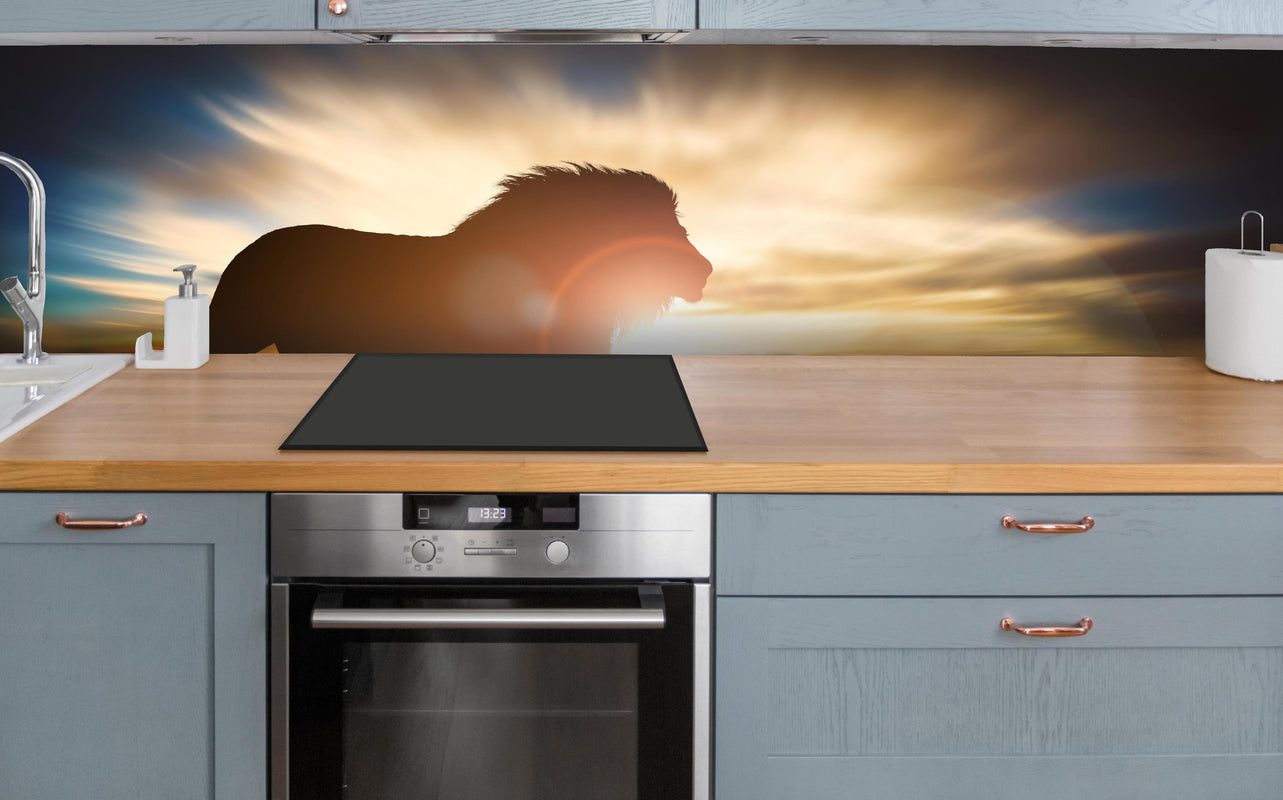 Küche - Silhouette eines großen erwachsenen Löwen in Afrika über polierter Holzarbeitsplatte mit Cerankochfeld