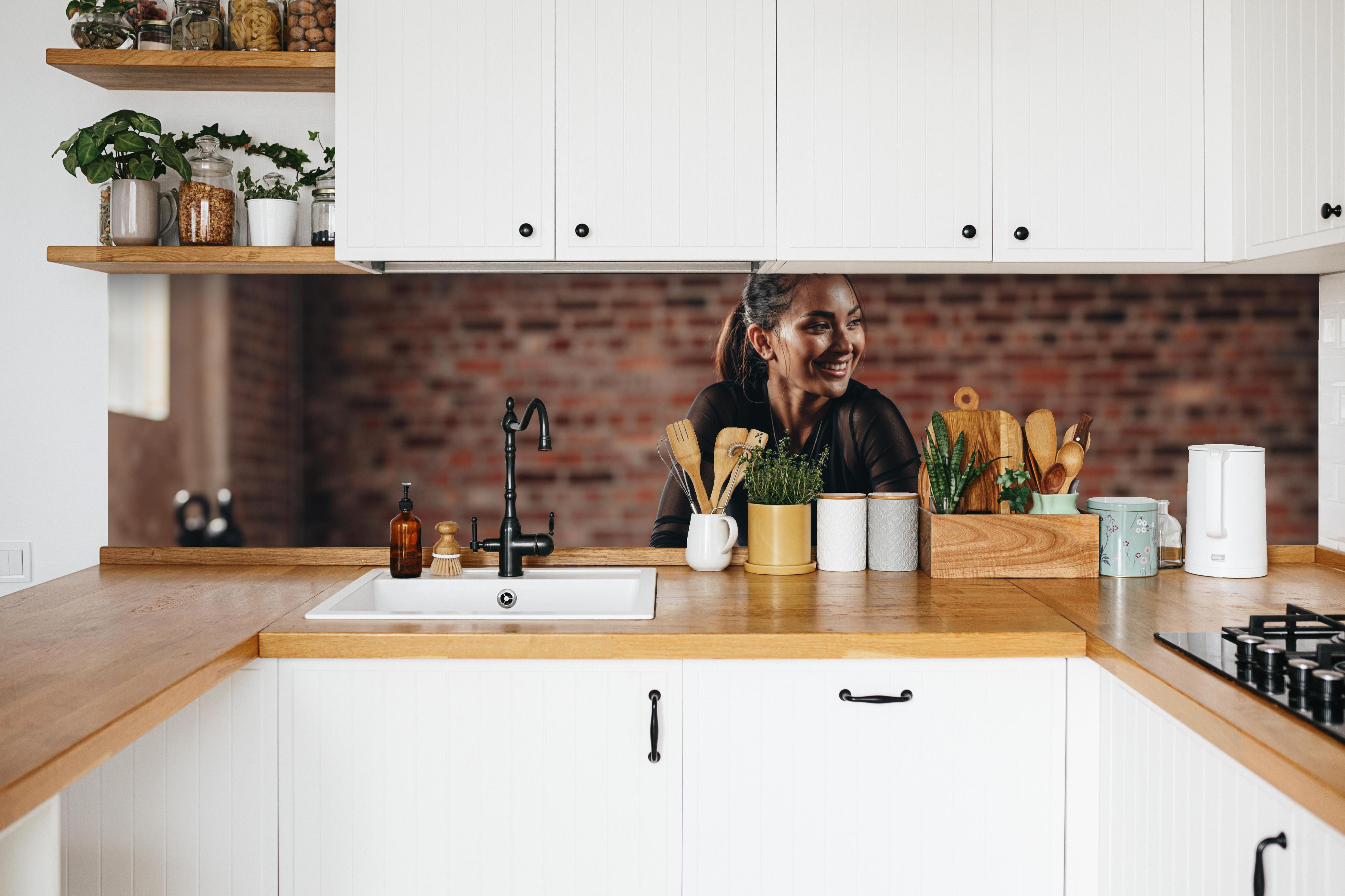 Küche - Sportlerin in der Hocke in weißer Küche hinter Gewürzen und Kochlöffeln aus Holz