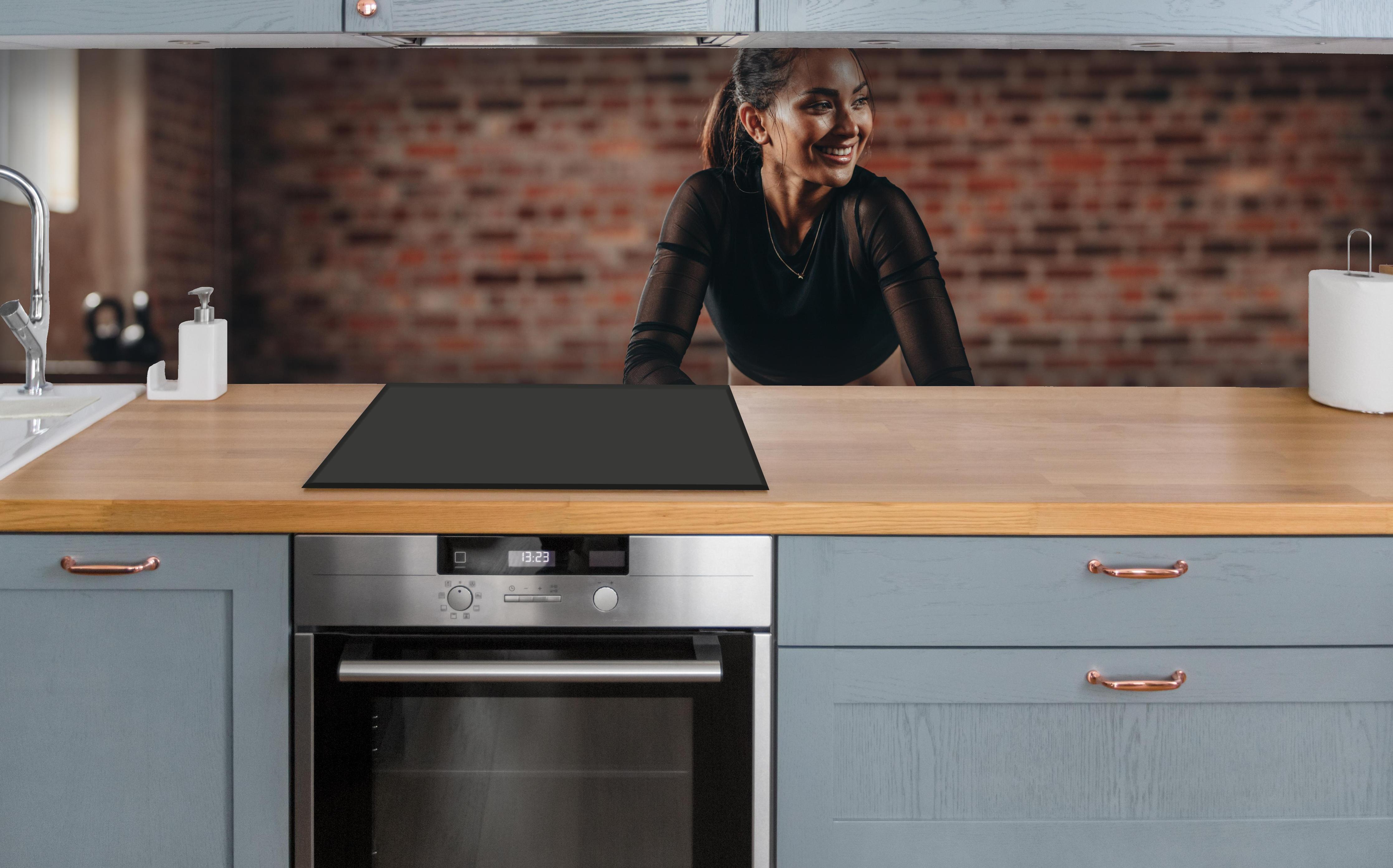 Küche - Sportlerin in der Hocke über polierter Holzarbeitsplatte mit Cerankochfeld