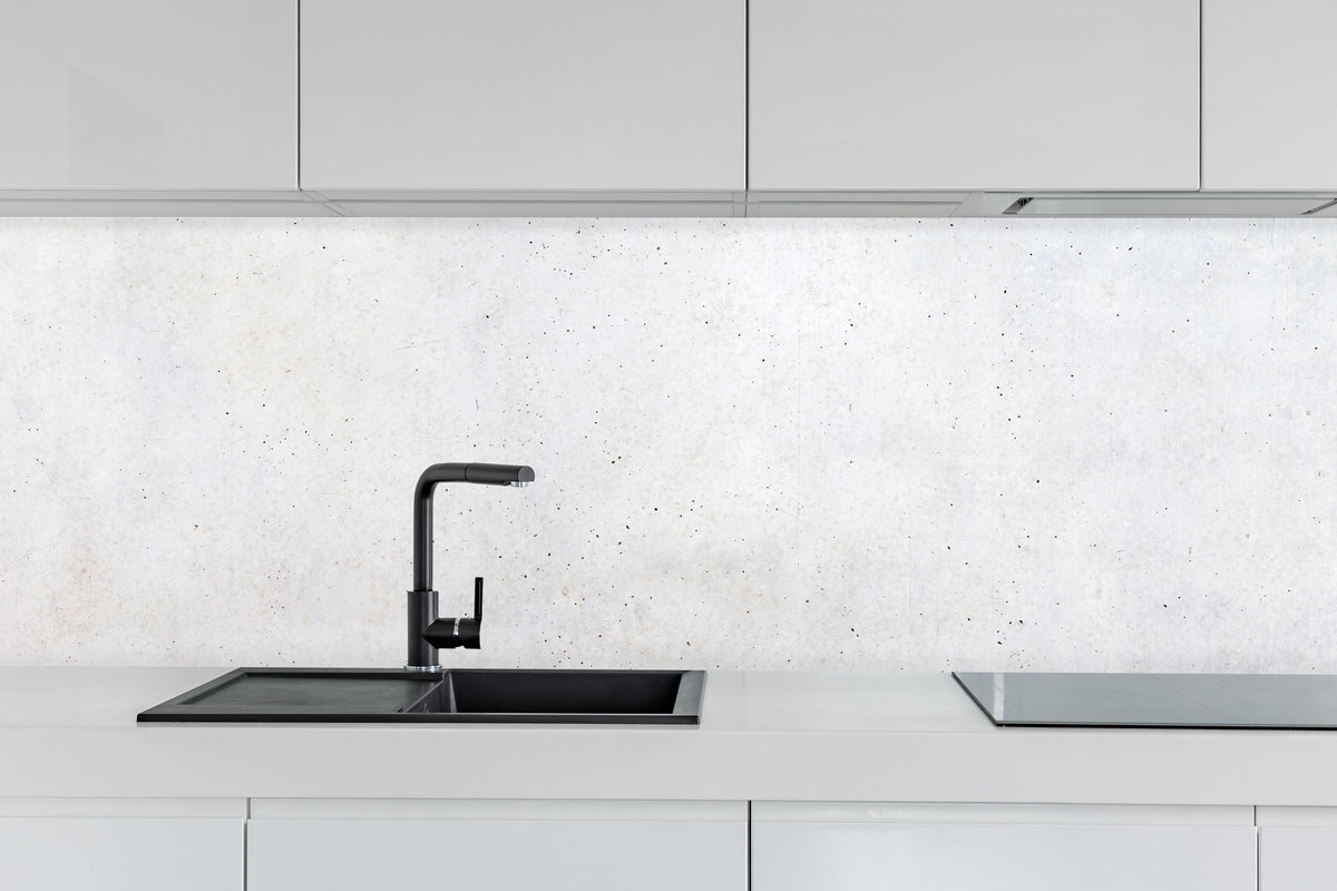 Küche - Textur einer weißen Betonwand hinter weißen Hochglanz-Küchenregalen und schwarzem Wasserhahn