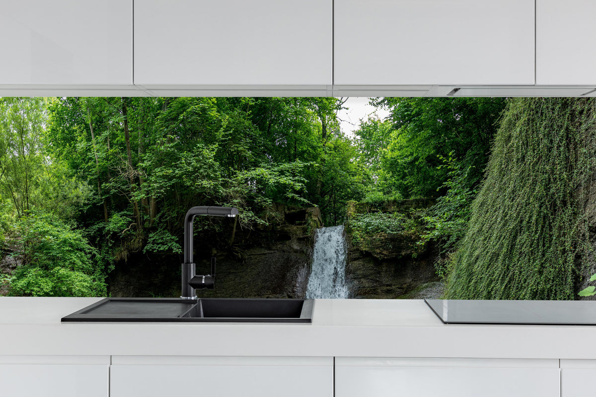Küche - Wasserfall im Wald - Utopie hinter weißen Hochglanz-Küchenregalen und schwarzem Wasserhahn