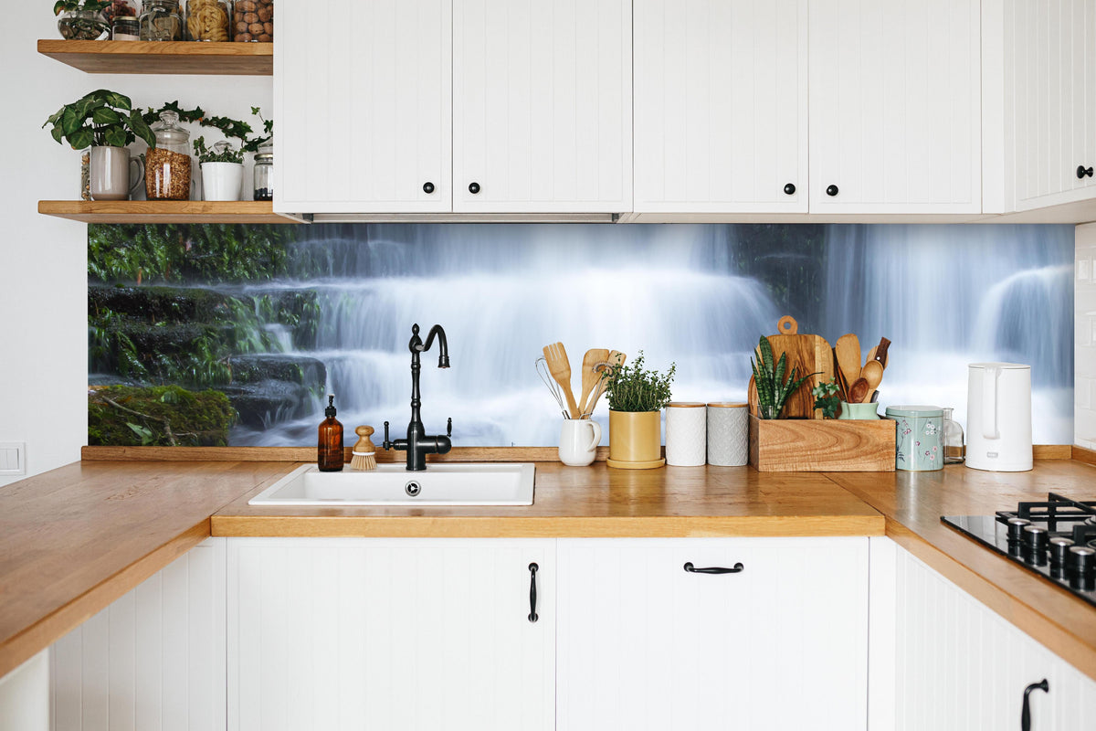 Küche - Wasserfall im Wald mit Felsen in weißer Küche hinter Gewürzen und Kochlöffeln aus Holz
