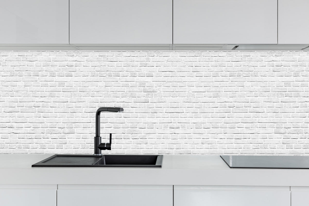 Küche - Weiß-Graue Backsteinmauer hinter weißen Hochglanz-Küchenregalen und schwarzem Wasserhahn