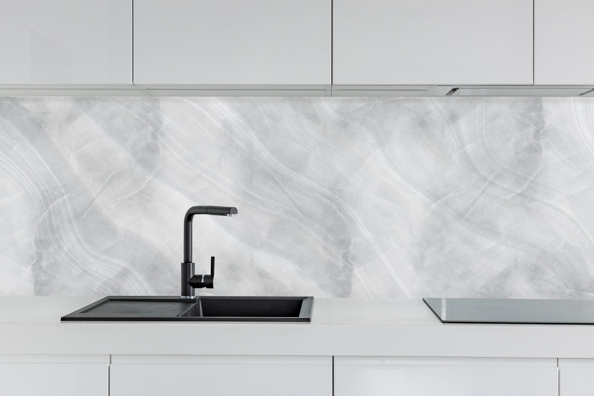 Küche - Weiß-Grauer Marmor hinter weißen Hochglanz-Küchenregalen und schwarzem Wasserhahn