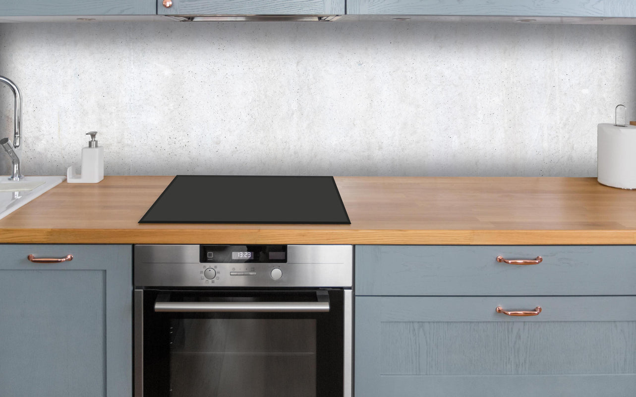 Küche - Weiß-bläuliche Betonwand über polierter Holzarbeitsplatte mit Cerankochfeld