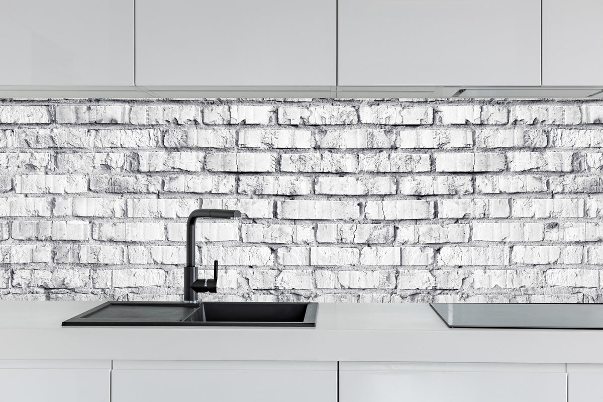 Küche - Weiß gekalkte Ziegelmauer hinter weißen Hochglanz-Küchenregalen und schwarzem Wasserhahn