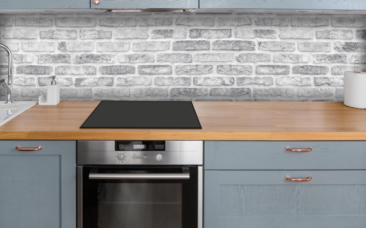 Küche - Weiß gewaschene Ziegelwand über polierter Holzarbeitsplatte mit Cerankochfeld