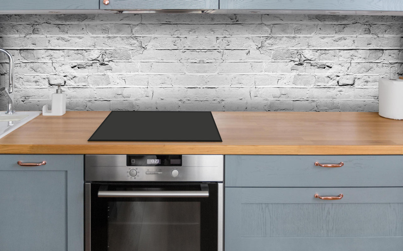 Küche - Weiß grau beschädigte Backstein Wand über polierter Holzarbeitsplatte mit Cerankochfeld